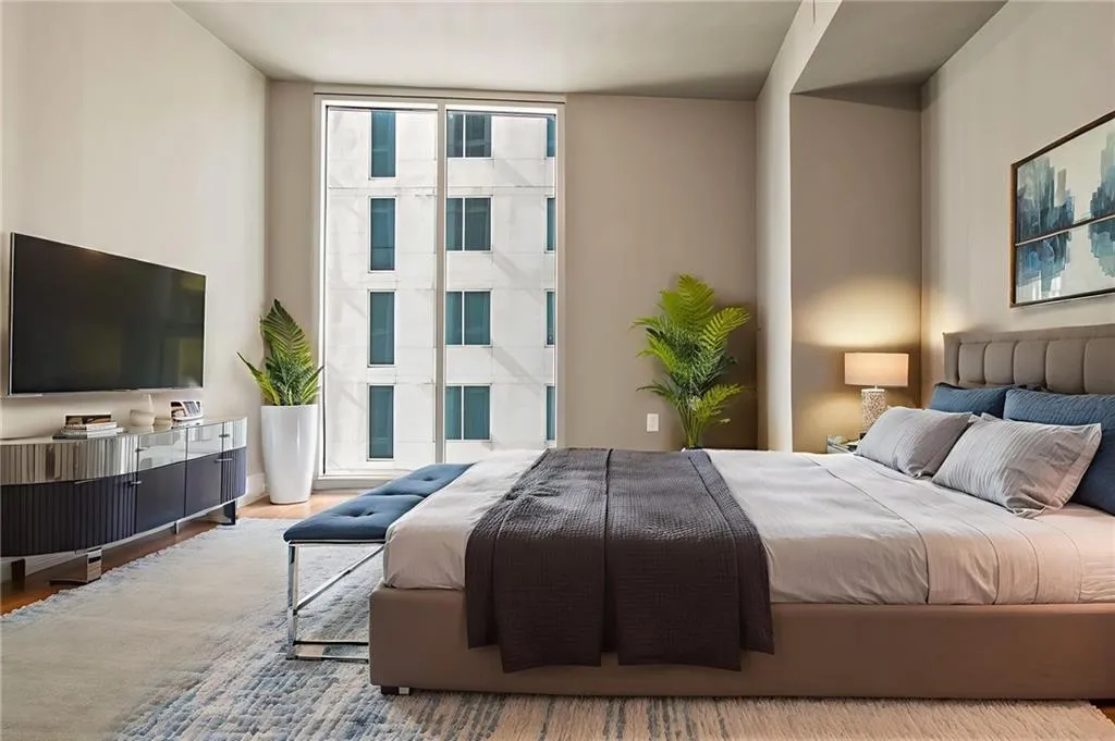 Bedroom featuring multiple windows, wood finished floors, and floor to ceiling windows