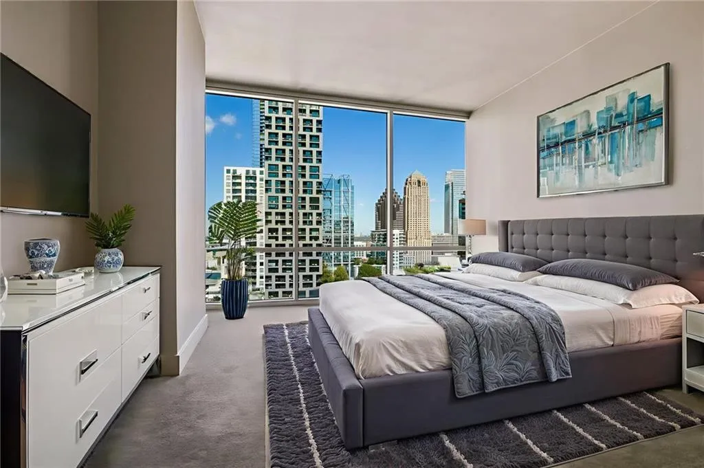 Bedroom featuring a view of skyline, a wall of windows, and carpet floors