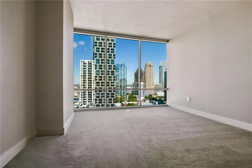 Carpeted empty room with floor to ceiling windows and a view of skyline