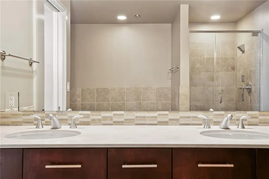 Bathroom with backsplash, a stall shower, and double vanity
