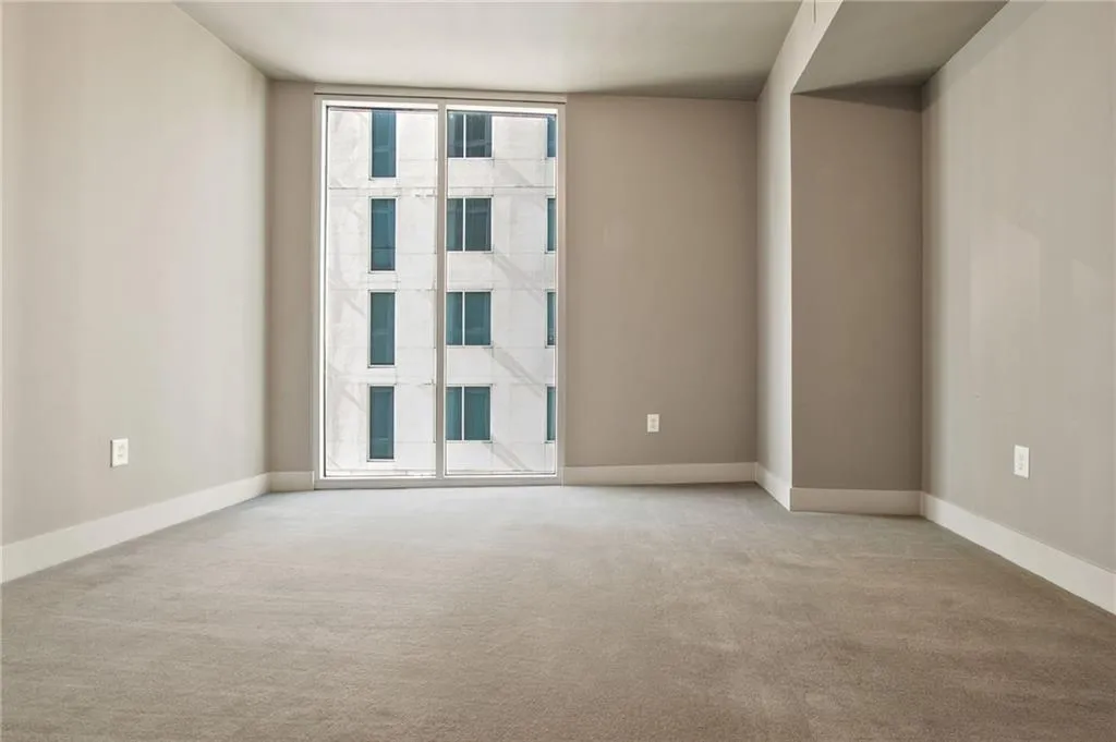 Unfurnished room featuring light colored carpet and floor to ceiling windows