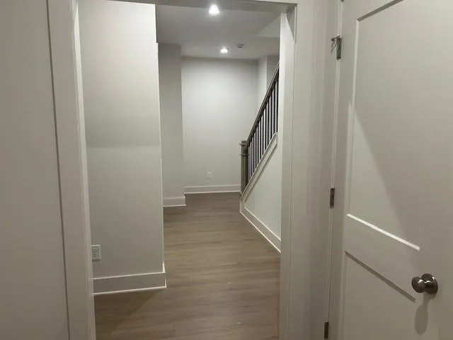 Hallway featuring wood finished floors, baseboards, stairs, and recessed lighting