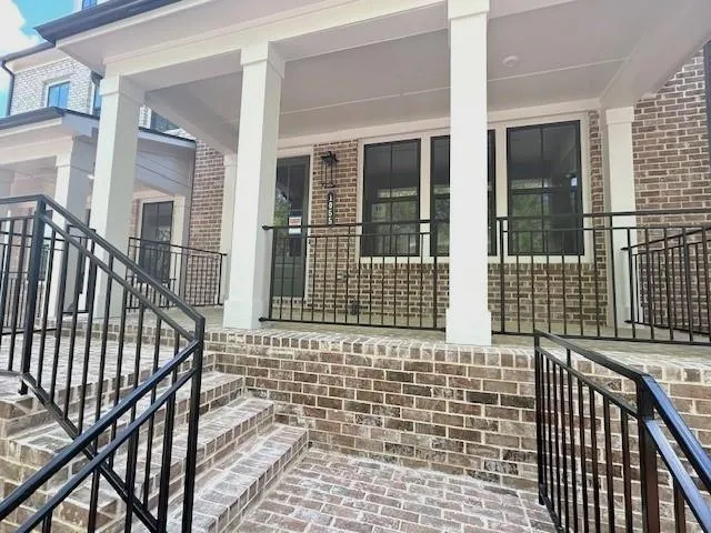 Doorway to property with a porch and brick siding