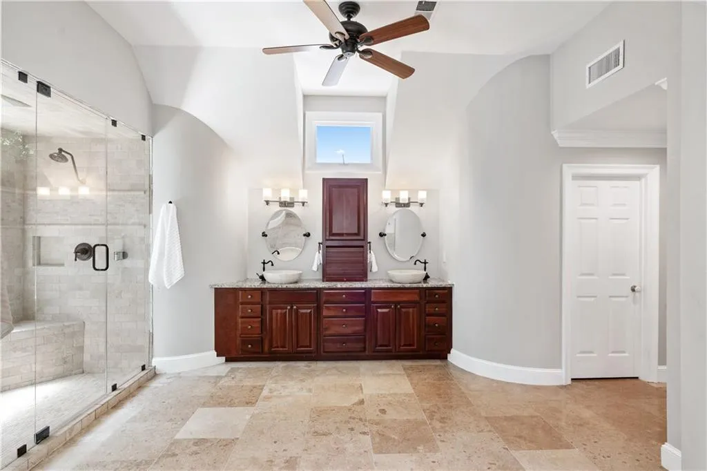 Ceiling fan, stone patterned flooring, dual vanity, and a dual shower