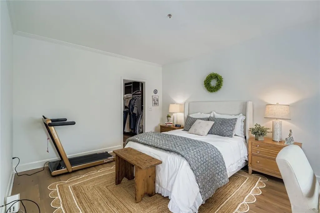 Bedroom with a spacious closet, wood finished floors, and crown molding