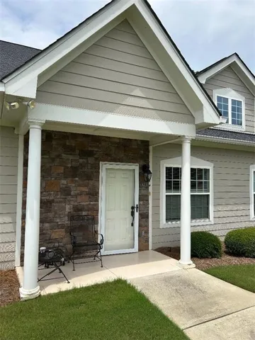 Front entrance featuring stone veneer siding, covered porch, and white paneled door