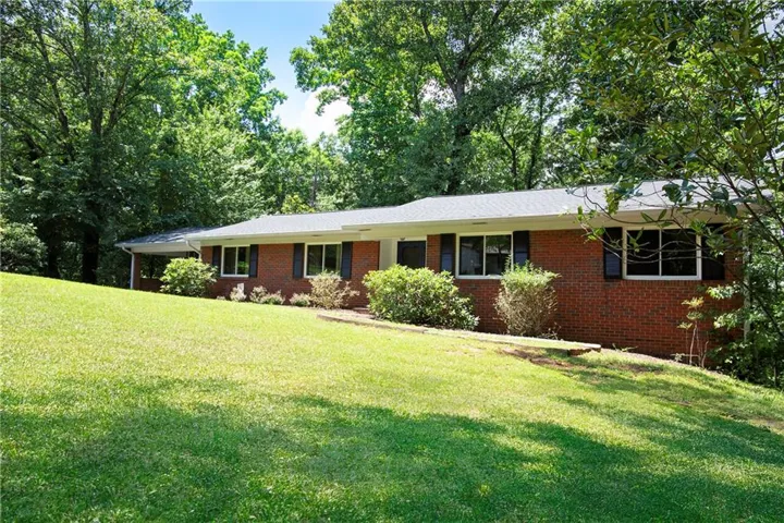 Traditional brick exterior featuring a white fascia, dark shutters, and a gray shingle roof