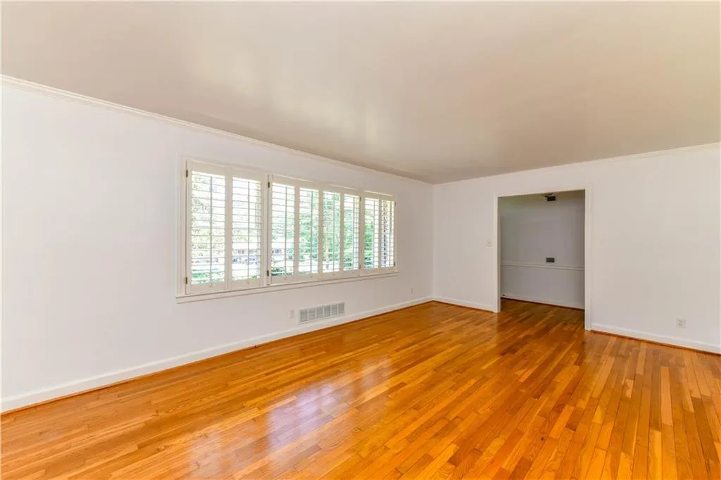 Empty room featuring baseboards, crown molding, visible vents, and light wood-type flooring