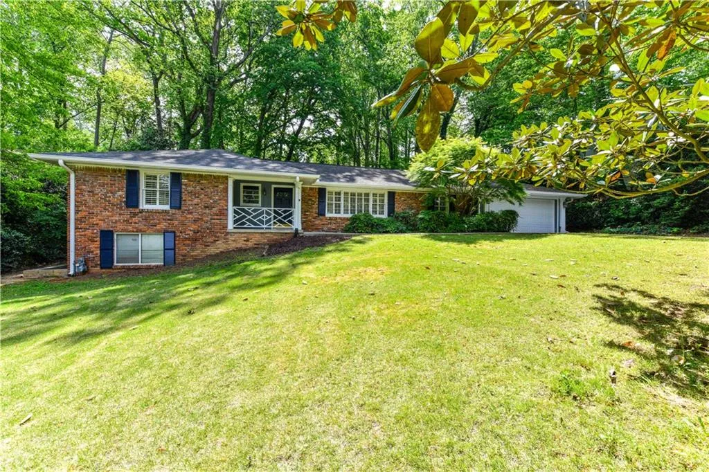 View of front of home featuring brick siding, an attached garage, and a front yard