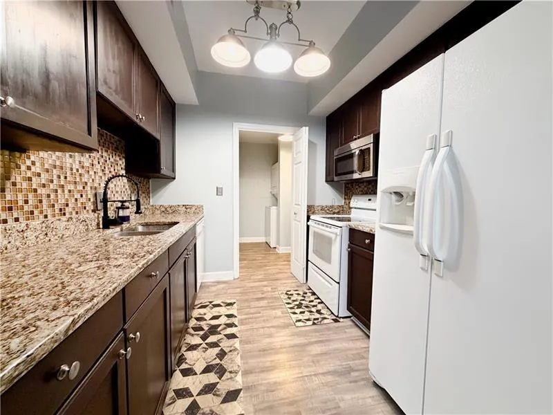 Kitchen featuring wood-finish flooring, dark wood cabinetry, and speckled countertops