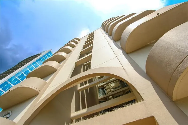 Architectural facade featuring arched openings, multiple levels of balconies, and a contrasting blue glass exterior