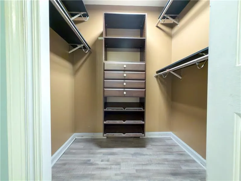 Walk-in closet with integrated shelving, drawers, and hanging rods