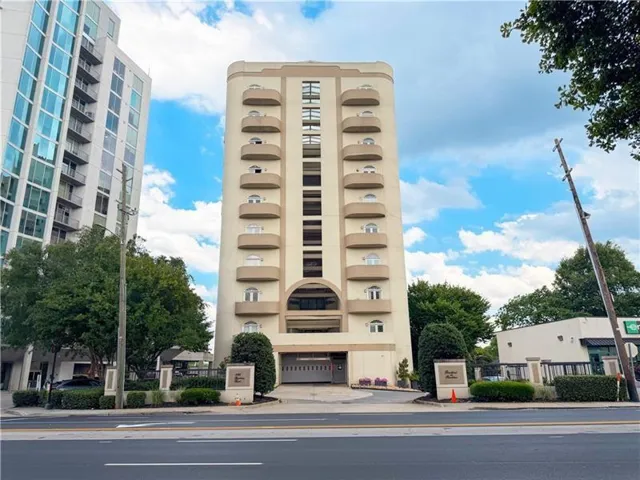 Multi-story building featuring individual balconies, arched windows, and a covered ground-level entrance