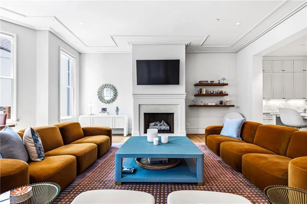 Spacious living area featuring a fireplace with a mantel, crown molding, large windows, recessed lighting, and wood-finish flooring