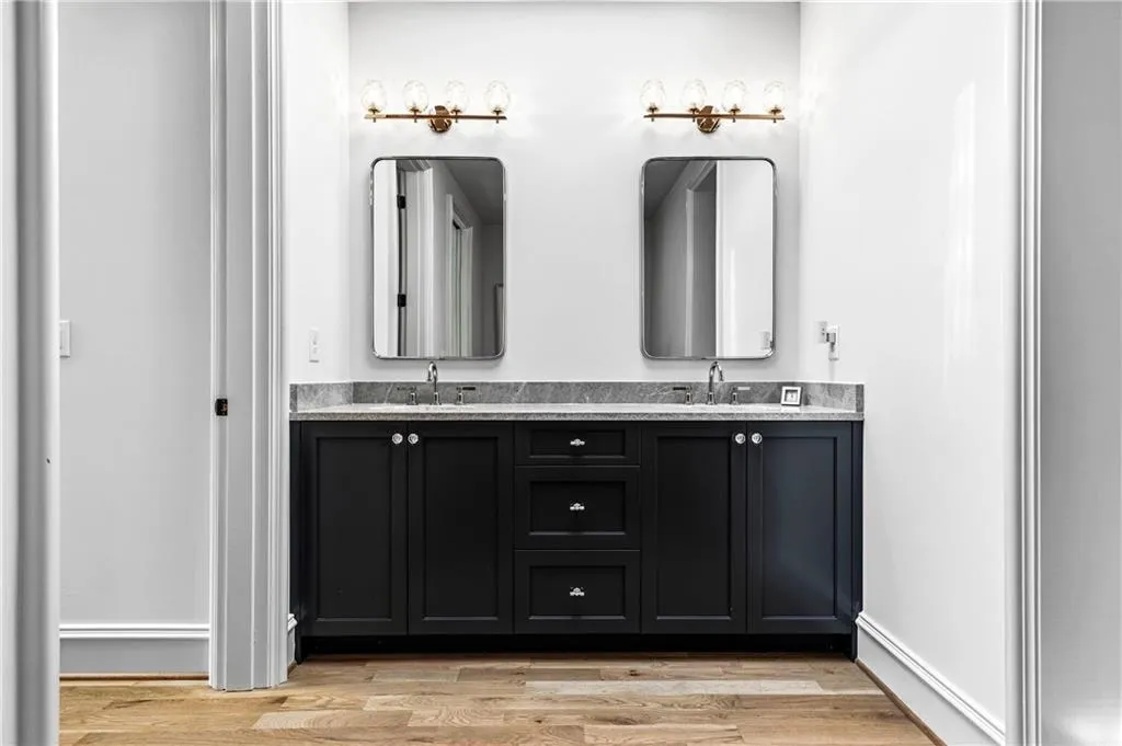 Dual sink vanity featuring dark cabinetry, a patterned countertop, and two framed mirrors