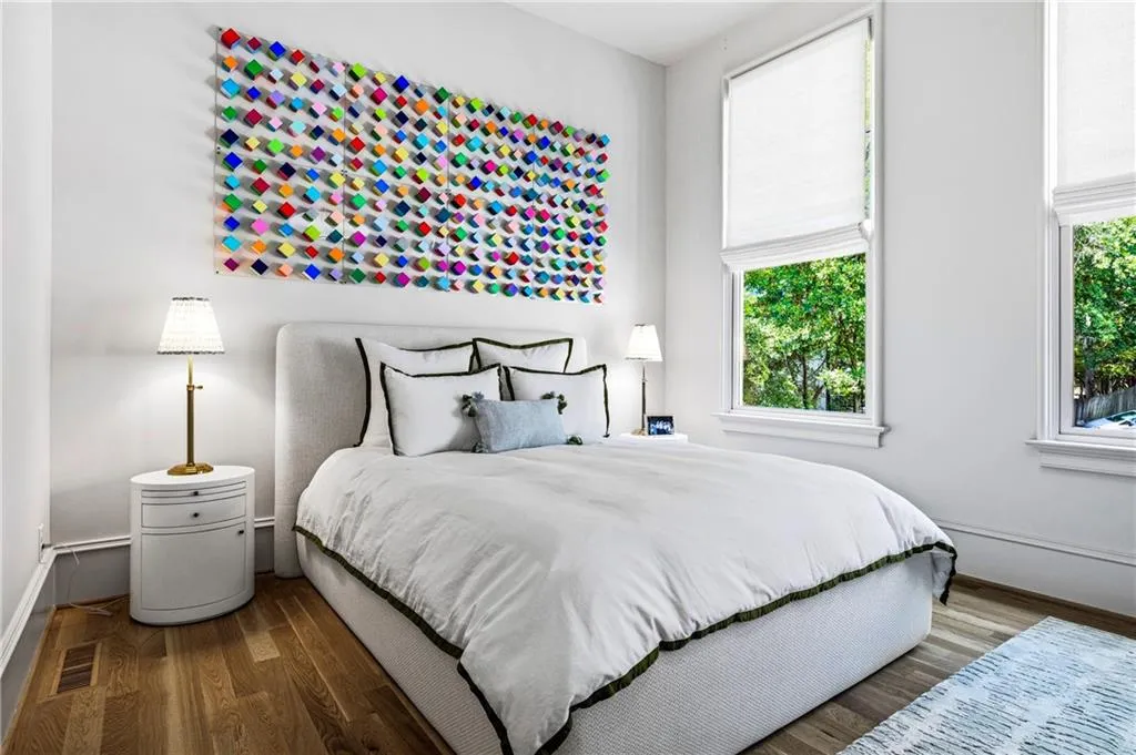 Bright room featuring two tall windows with white window treatments, wood-finish flooring, and white baseboards