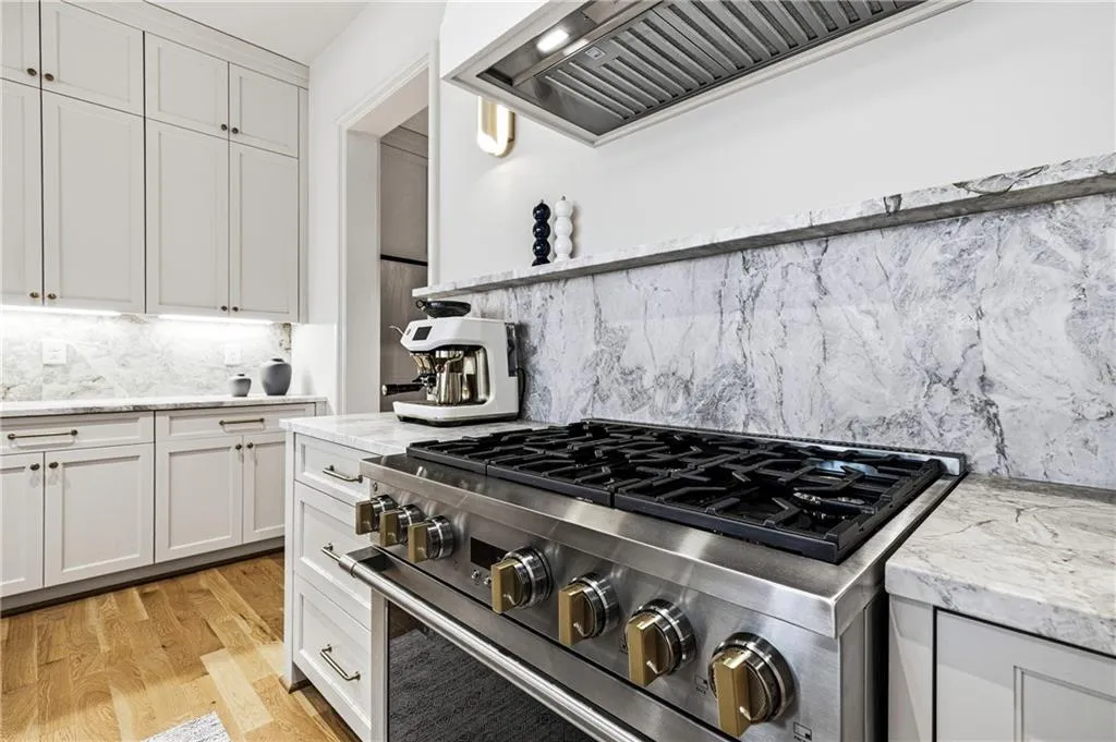 Stainless steel gas range with gold-tone hardware, complemented by a matching stainless steel range hood