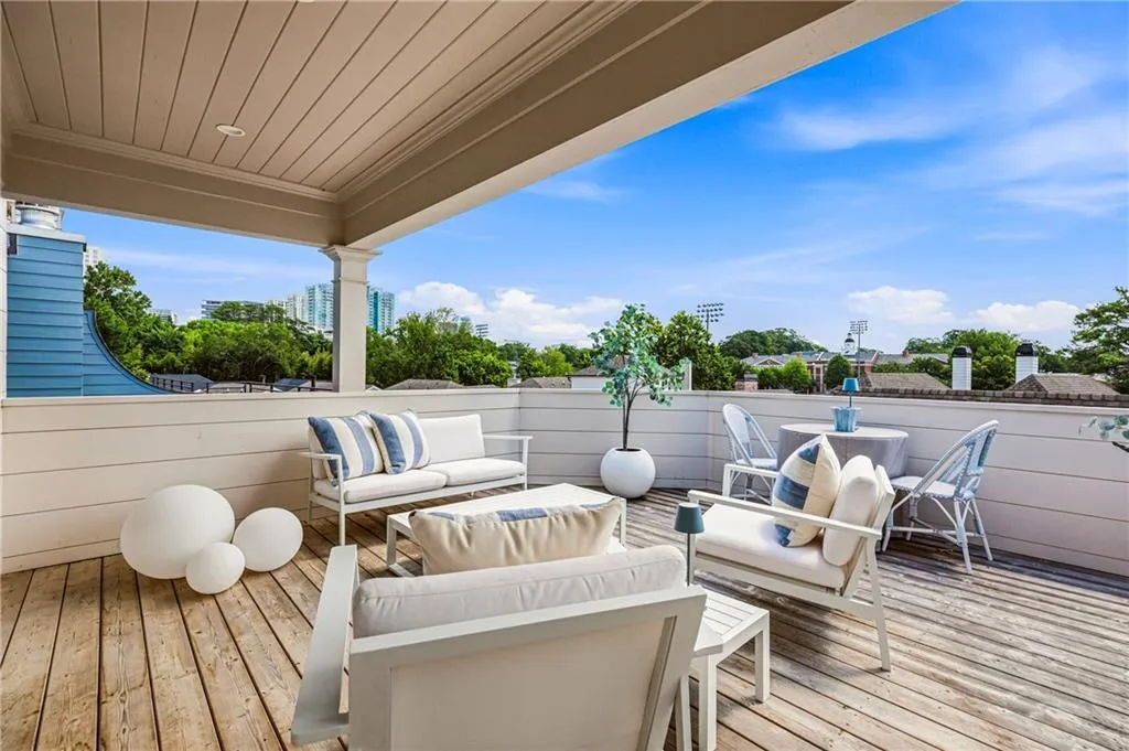 Expansive rooftop deck featuring wood-finish flooring, a covered patio area, and a surrounding privacy wall