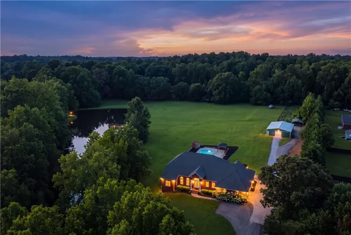 Expansive property featuring a private pond, large green lawn, and a dark-bottom swimming pool