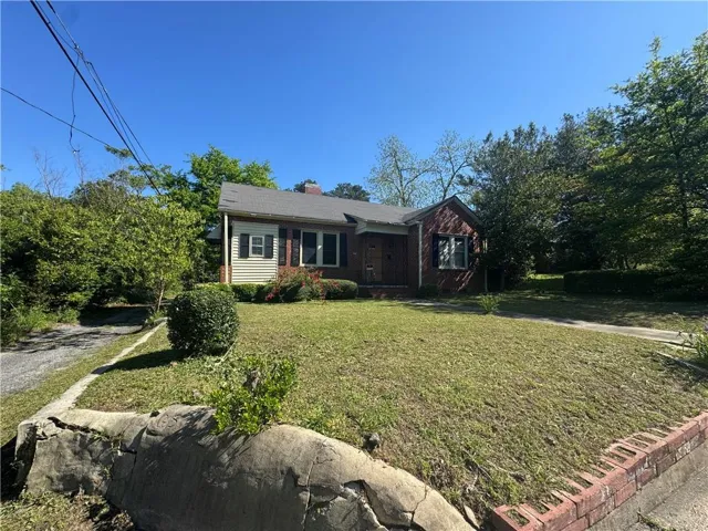Single-story residence featuring a brick and siding exterior, a front yard with mature landscaping, and an asphalt driveway