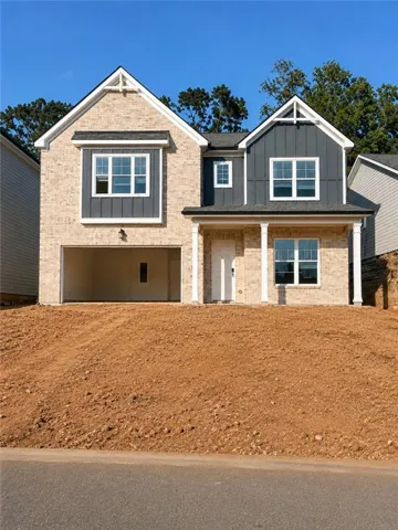Brick exterior with board and batten accents, two-car garage, and covered entry with columns