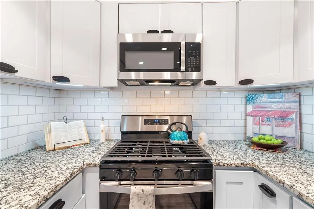 Kitchen featuring white cabinetry, light stone countertops, and stainless steel appliances