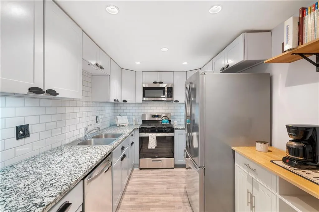 Kitchen with white cabinetry, appliances with stainless steel finishes, sink, and tasteful backsplash
