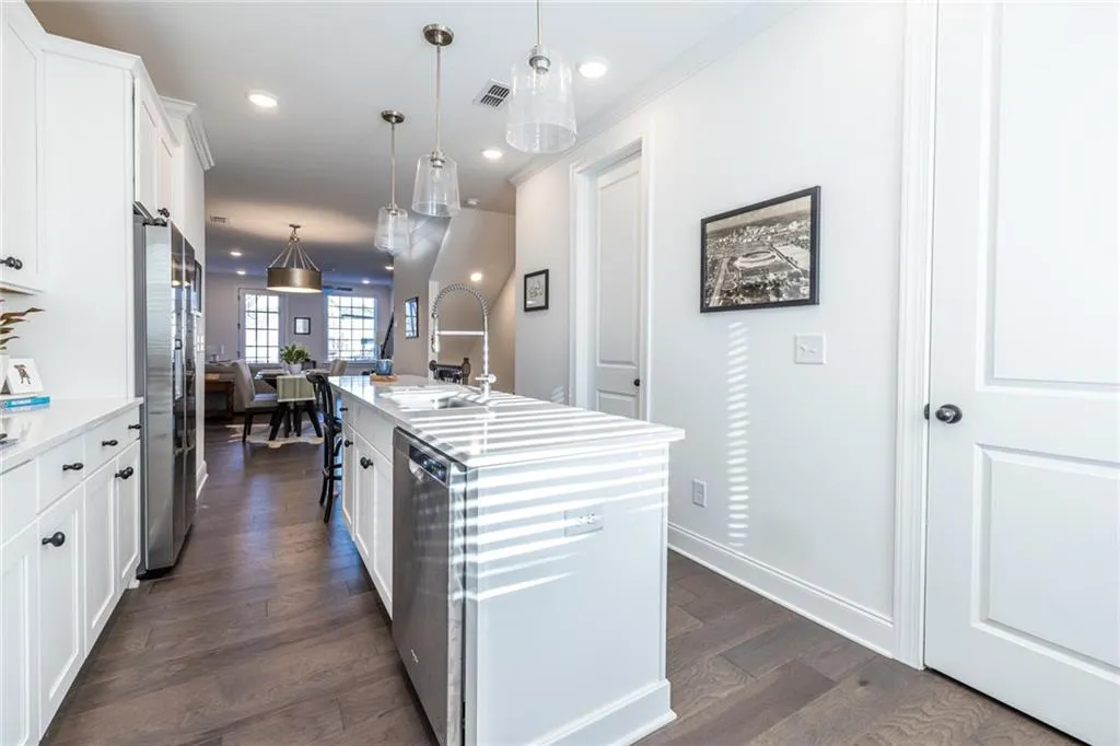 Kitchen with an island with sink, stainless steel appliances, white cabinets, dark wood finished floors, and light countertops