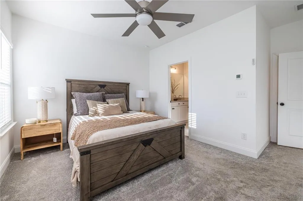 Bedroom featuring light carpet, multiple windows, and ensuite bathroom