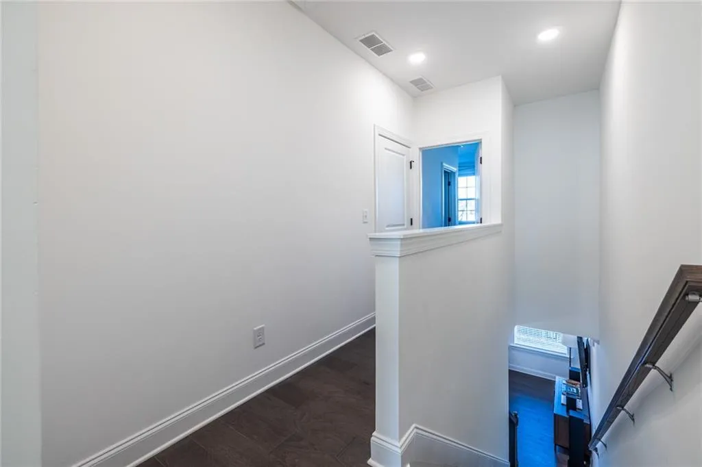Hall with an upstairs landing, dark wood-type flooring, and recessed lighting