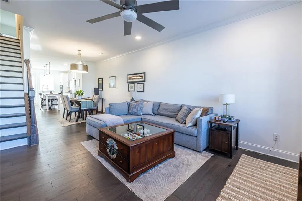 Living room featuring stairs, ceiling fan, dark wood finished floors, crown molding, and recessed lighting