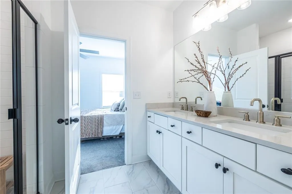 Ensuite bathroom with double vanity, a stall shower, and marble finish floors
