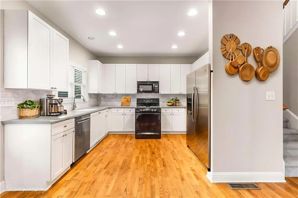 Kitchen with white cabinets, black appliances, light wood finished floors, backsplash, and recessed lighting