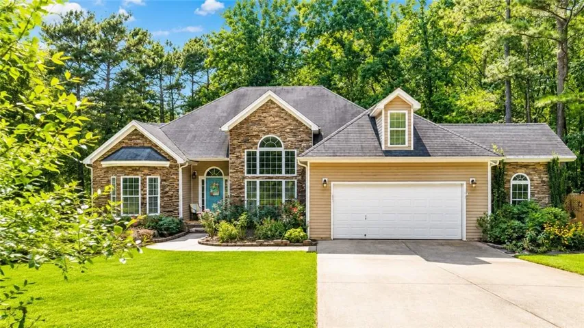 Stone and siding exterior with a prominent arched window, dormer, and attached garage