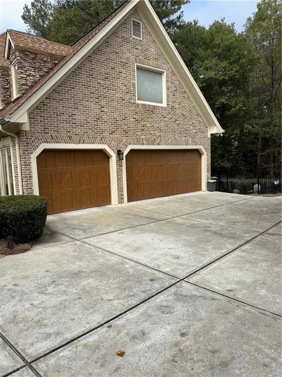 View of property exterior featuring brick siding and concrete driveway
