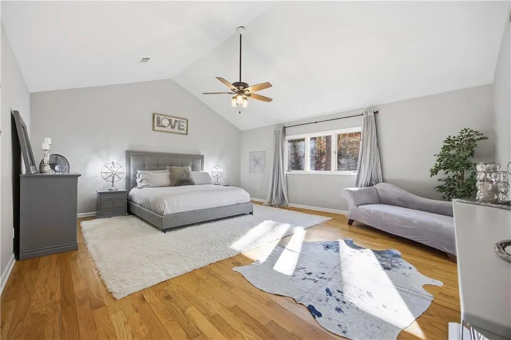 Enormous, light-filled primary suite featuring vaulted ceilings, sitting area, and hardwood floors