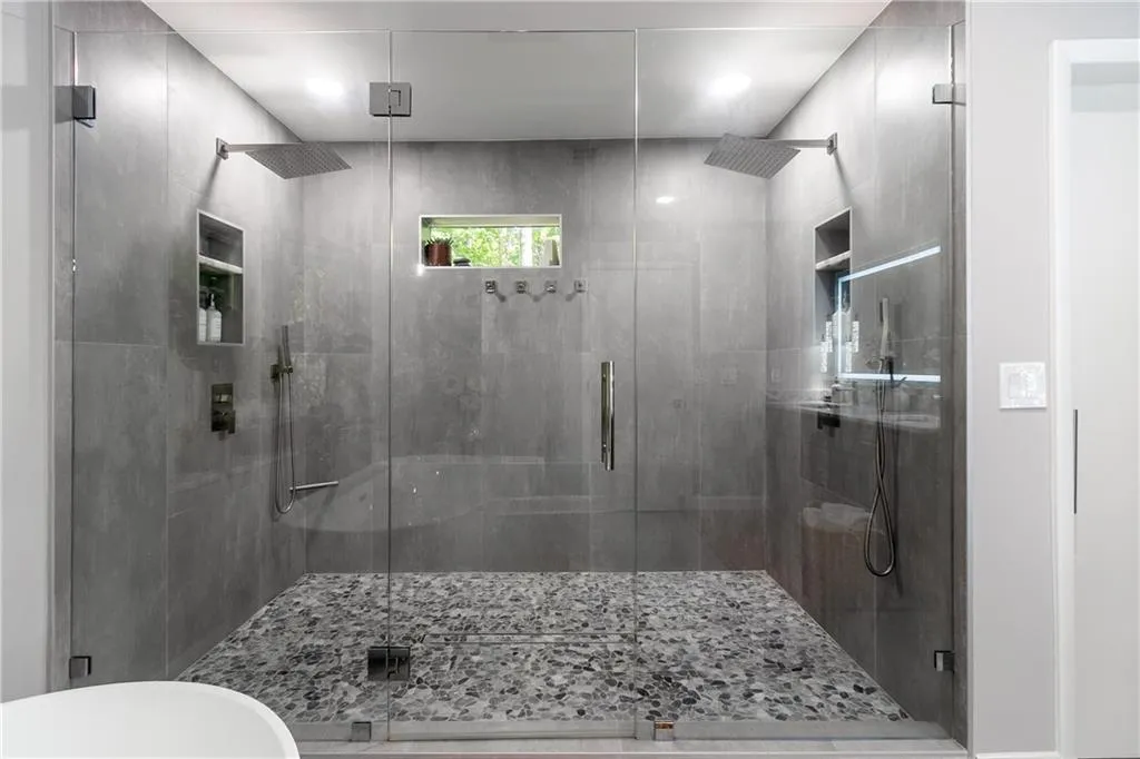 Walk-in shower with dual rain showerheads, floor-to-ceiling tile, and frameless glass enclosure