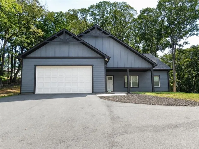 Contemporary exterior with vertical siding, a two-car garage, covered entry, and a paved driveway