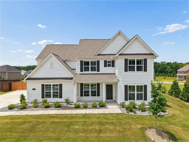 Traditional-style residence featuring white siding and dark shutters