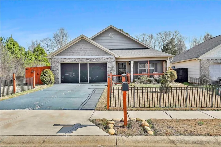 View of front of house featuring a fenced front yard, covered porch, driveway, and an attached garage