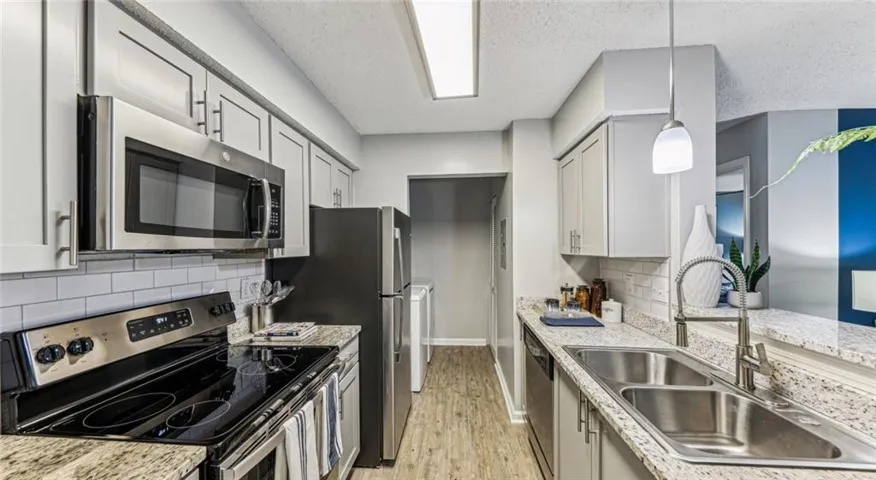 Kitchen featuring light wood-type flooring, appliances with stainless steel finishes, a textured ceiling, and sink
