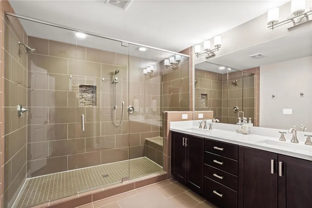 This shower rivals that of a high end hotel with dual shower heads and a built in bench don't miss the dual sink vanity with optimal drawer storage