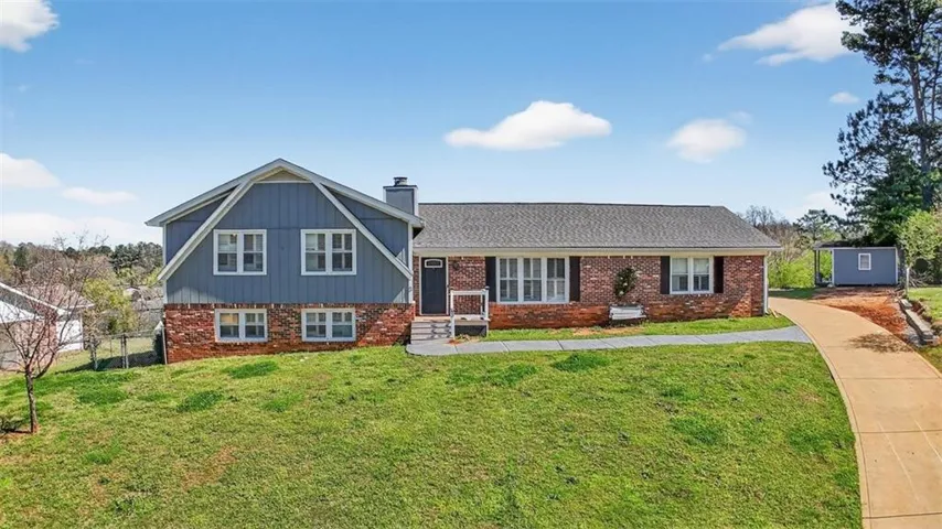 Tri-level home with brick siding, a chimney, and a shingled roof