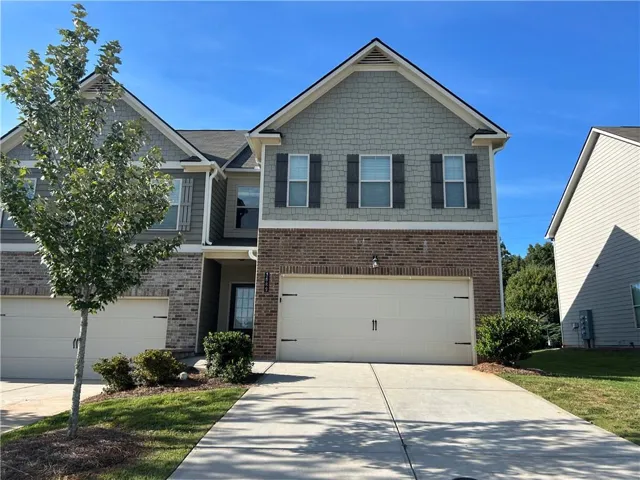 Two-story exterior with brick and siding, featuring a two-car garage, front entry, and mature landscaping