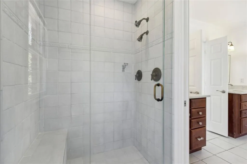 Glass enclosed dual head shower with tile bench