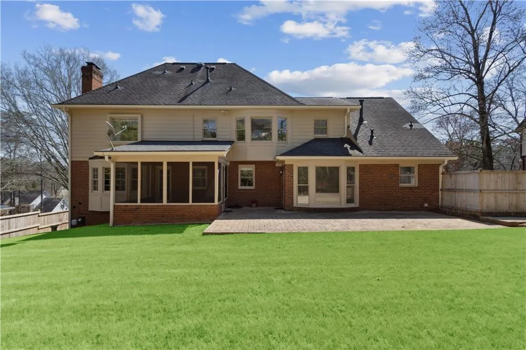 Rear view of house with a patio, a yard, fence, and a sunroom