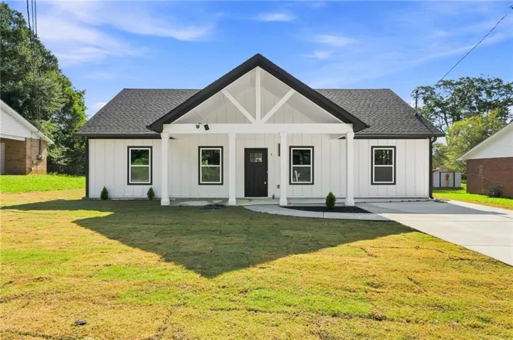 Modern farmhouse residence featuring a symmetrical façade with board-and-batten siding, dark gable roof, and decorative timber X-bracing