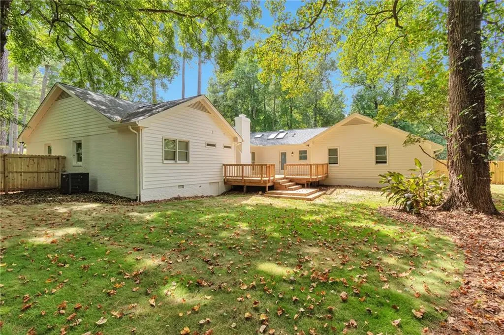 Back of house with central AC, a yard, and a deck