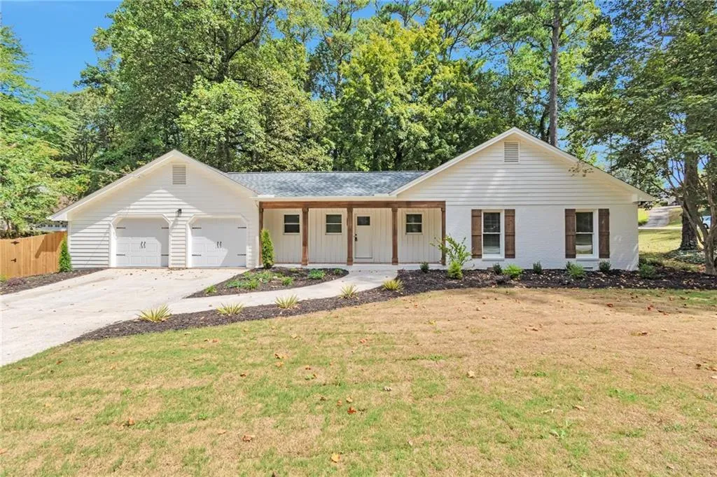 Ranch-style house with a porch, a garage, and a front lawn