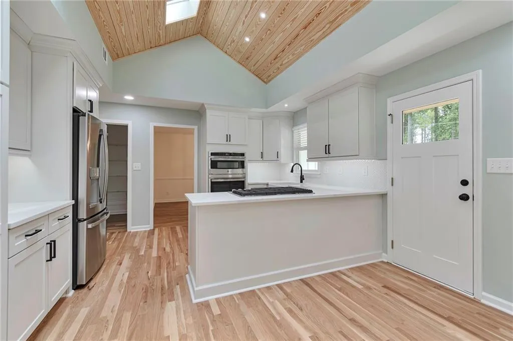 Kitchen with wooden ceiling, light hardwood / wood-style flooring, appliances with stainless steel finishes, lofted ceiling, and white cabinets